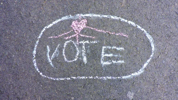 The word "Vote" spelled out in chalk on sidewalk